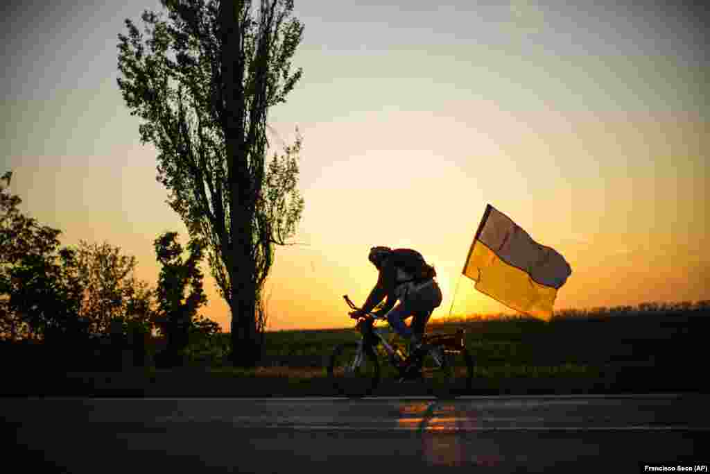 A man rides a bicycle with a Ukrainian flag on the road between Odesa and Mykolayiv.