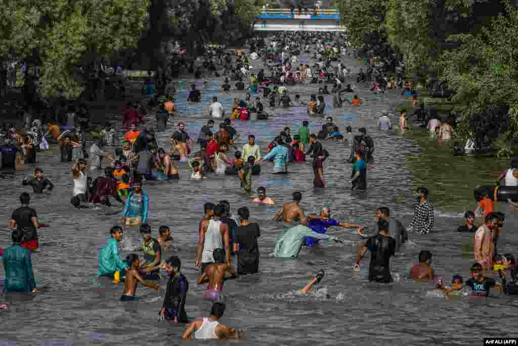 People cool themselves in a canal on a hot summer day in Lahore, Pakistan.