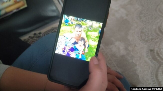 Молдир Калиаскарова показывает в телефоне фото мужа Айдоса Алдашова с ребенком