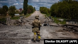 Украинский военный у разрушенного моста в Харьковской области, май 2022 года