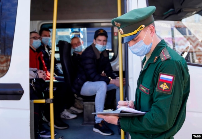 Conscripts board a shuttle bus at a recruitment center in Kalingrad before departing for military service with the Russian Army.