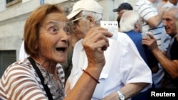 O pensionară la Atena, primind numărul de rând pentru ridicarea pensiei, la o filială a Băncii Naţionale a Greciei, 1 iulie 2016.