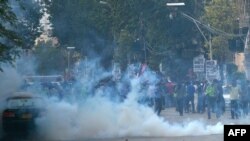 Policemen fire teargas canisters to scatter protesters during the march toward the U.S. consulate in Karachi on August 27.