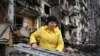 Женщина на разборе завалов на месте поврежденного жилого дома в пригороде Киева, 25 февраля 2022 года