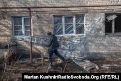 Workers move to replace windows shattered by a round of artillery in Novoluhanske on February 22.