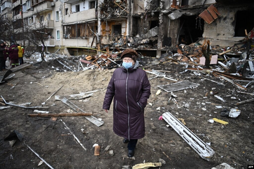 Një grua ecën para një ndërtese banimi të dëmtuar në rrugën Koshytsa, një periferi të kryeqytetit ukrainas Kiev, ku dyshohet se goditi një predhë ushtarake, më 25 shkurt 2022.