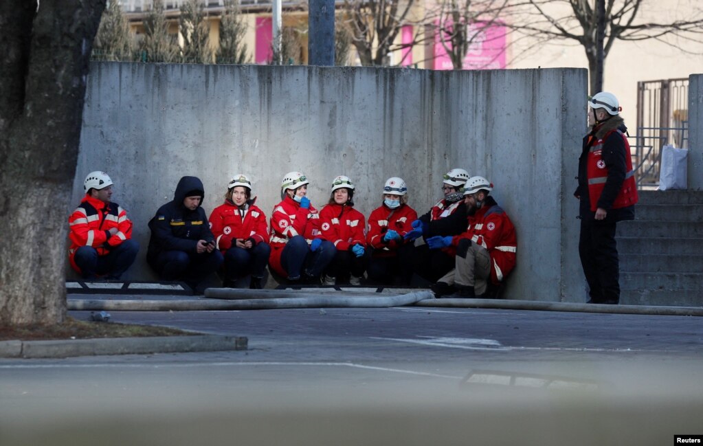 Pjesëtarët e ndihmës së parë shihen duke u fshehur pasi bien sirenat për sulme ajrore në një zonë të banuar në Kiev më 26 shkurt.   