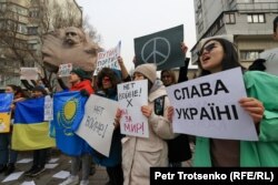 Люди с антивоенными плакатами и флагами Украины на митинге в поддержку Украины в Алматы. 26 февраля 2022 года