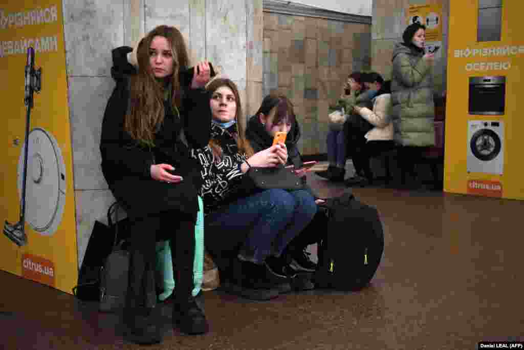 Girls hold their mobile phones as they take refuge in a subway station in Kyiv. Air raid sirens rang out in downtown Kyiv as cities across Ukraine were hit with Russian missile strikes and artillery.
