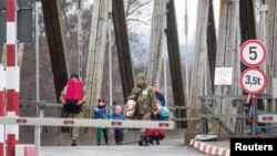 UKRAINE- Ukranian soldiers help a woman and children cross the border at Sighetu Marmatiei Customs point, in Baia Mare, Romania, February 26, 2022.