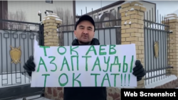 Гражданский активист Макс Бокаев с плакатом «Тоқаев, азаптауды тоқтат» («Токаев, прекрати пытки») перед зданием прокуратуры. Атырау, 14 января 2022 года