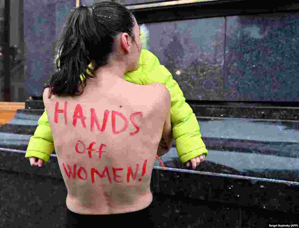 Активістка-феміністка FEMEN разом із донькою протестує біля Офісу президента України проти урядового проєкту військового обліку для жінок. Київ, Україна. 27 січня 2022 року