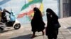 Iranian women walk next to a wall painting of Iran’s national flag in a street in the capital, Tehran. (file photo)