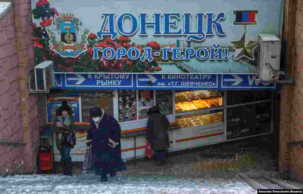 People walk through a pedestrian tunnel under a sign declaring &quot;Donetsk Hero City&quot; in the separatist-held city of Donetsk.