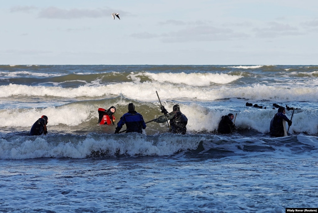 Burrat po përdorin rrjeta dore për t'i hequr mbeturinat e grumbulluara nga një stuhi që goditi Detin Baltik më 17 janar. Erërat atë ditë frynë deri në 82 kilometra në orë.