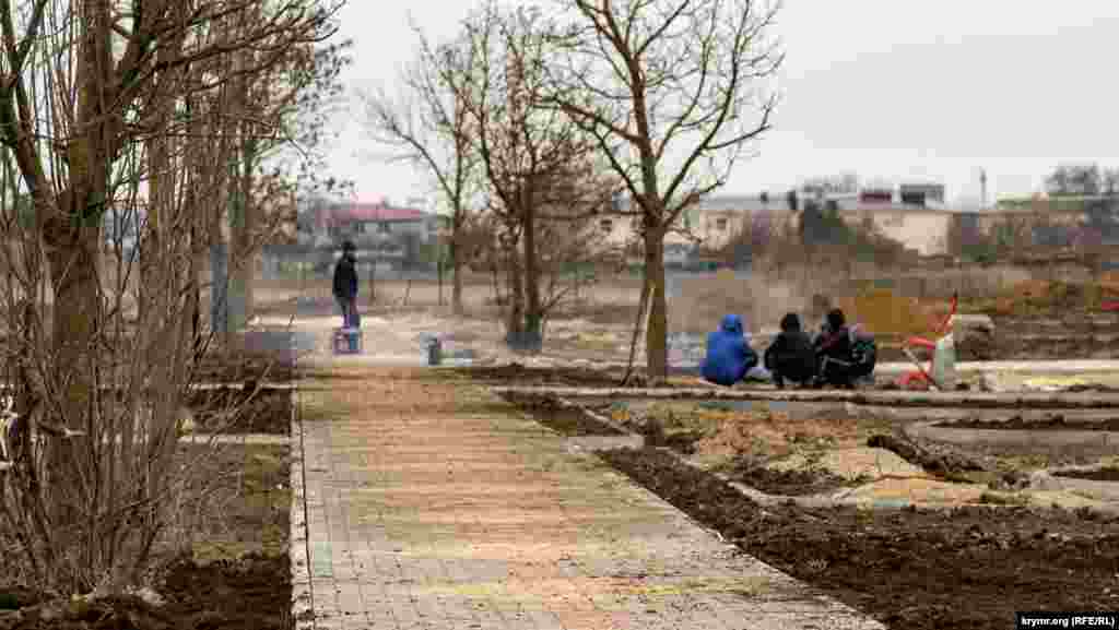 Робітники, задіяні в капремонті коштом уряду Москви території загального користування, разом із місцевими хлопчиками гріються біля багаття