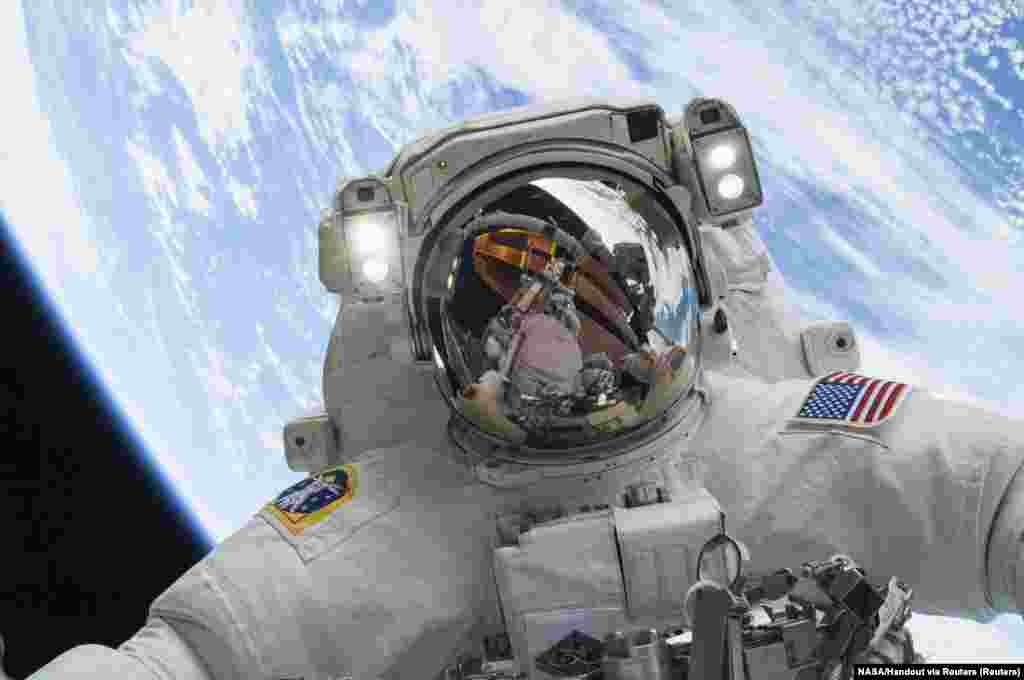 Mike Hopkins űrhajós, az Expedition 38 fedélzeti mérnöke űrsétát tesz 2013. december 24-én a sisakján tükröződő&nbsp;Rick Mastracchio űrhajóssal, hogy kicseréljék a Nemzetközi Űrállomás külsején meghibásodott vízszivattyút