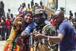 Жители Конакри, столицы Гвинеи, фотографируются с вышедшими на улицы военными. 6 сентября 2021 года
