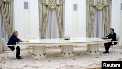 На фото з переговорів видно, що Макрон і Путін спілкуються, сидячи на протилежних кінцях кількаметрового стола