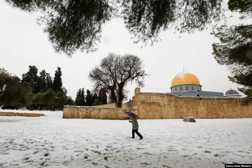 Një burrë duke ecur pranë Kupolës së Shkëmbit, që ndodhet në qytetin e vjetër të Jerusalemit gjatë një mëngjesi me borë.