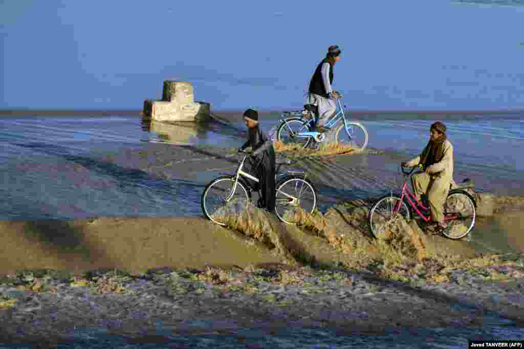 Afghan boys ride bicycles in floodwater along a stream in the Daman district of Kandahar.