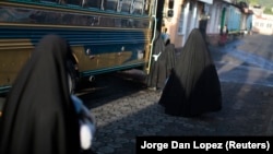 Female members of the Lev Tahor Jewish community walk toward a bus as they prepare to leave the village of San Juan La Laguna, Guatemala, in August 2014. 