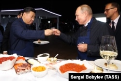 Қытай басшысы Си Цзиньпин (сол жақта) және Ресей президенті Владимир Путин Владивостоктағы кездесу кезінде стақан соғыстырып тұр.