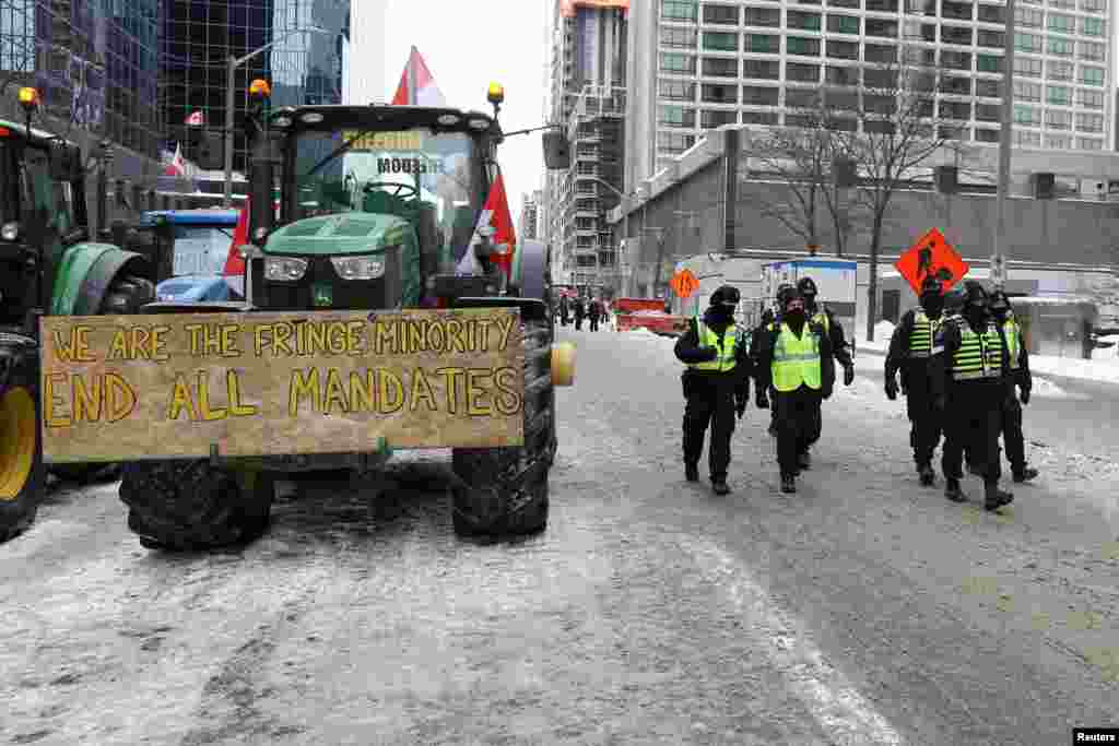 Policajci prolaze pored parkiranih bagera za vrijeme protesta kamiondžija, Ottawa, 6. februar 2022.