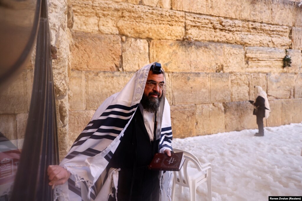 Një hebre ultra-ortodoks mban libër lutjesh në Murin Perëndimor, në një mëngjes me dëborë në qytetin e vjetër të Jerusalemit. &nbsp;