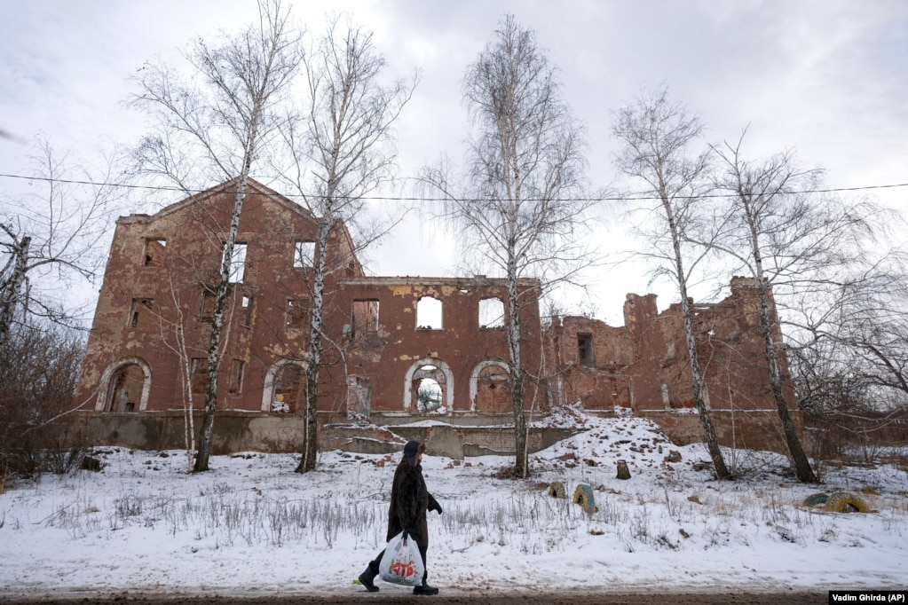Një banore lokale kalon pranë një ndërtese të shkatërruar nga luftimet ndërmjet ushtrisë ukrainase dhe separatistëve më 2014. Kjo fotografi është realizuar më 30 janar në periferi të Slovyansk në rajonin Donetsk.