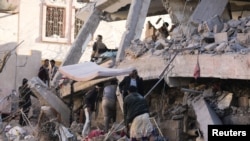 A rescuer searches for survivors under the collapsed roof of a house hit by Saudi-led air strikes in Sanaa, Yemen, on January 18.