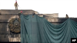 Рабочие завешивают здание городского акимата Алматы, горевшее во время январских событий