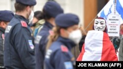 A koronavírus-járvány miatti intézkedések ellen tüntetők az osztrák kancellária előtt az új kancellár eskütételi ünnepségén Bécsben, 2021. december 6-án. A transzparensen a felirat: „Ez a kormány a nép ellen lép fel, és azonnal le kell mondania”