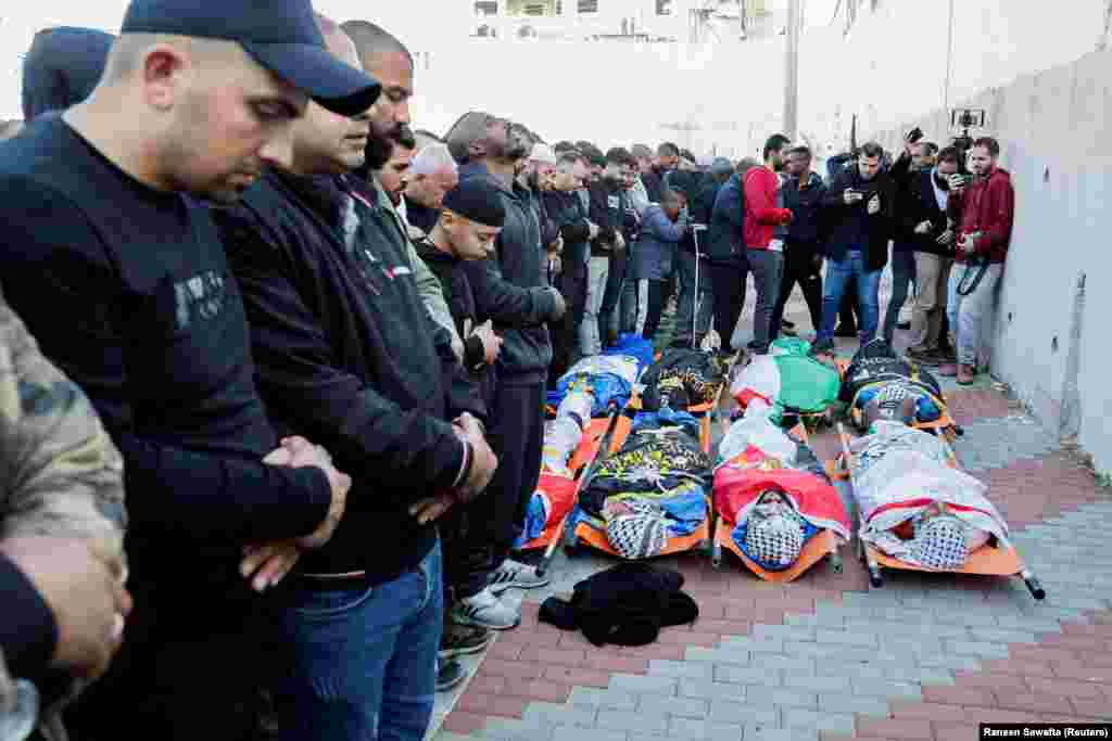 Pjesëmarrësit në një funeral duke u falur para trupave të pajetë të palestinezëve të vrarë nga operacioni izraelit.