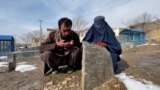 Kabul, Afghanistan -- Parents on the grave of their infant son who died of extreme cold in Afghanistan 