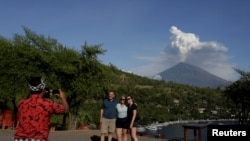  Гид снима туристи на фона на вулкана Агунг, който е най-високият връх в Бали 