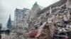 Disa njerëz duke qëndruar para ndërtesave të shembura, pas një tërmeti në Kahramanmarash, Turqi, më 6 shkurt 2023.