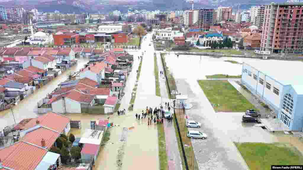 Banorët duke qëndruar mes një rruge në një lagje të përmbytur në Mitrovicën e Jugut.