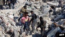 Një person mban në duar një fëmijë të nxjerrë nga rrënojat në qytetin Harim, në provincën Idlib të Sirisë. 8 shkurt 2023.