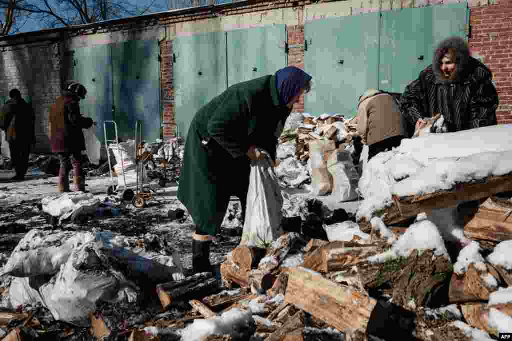 Ljubov tűzifát gyűjt az utcán lévő, hólepte, felhasogatott kupacból