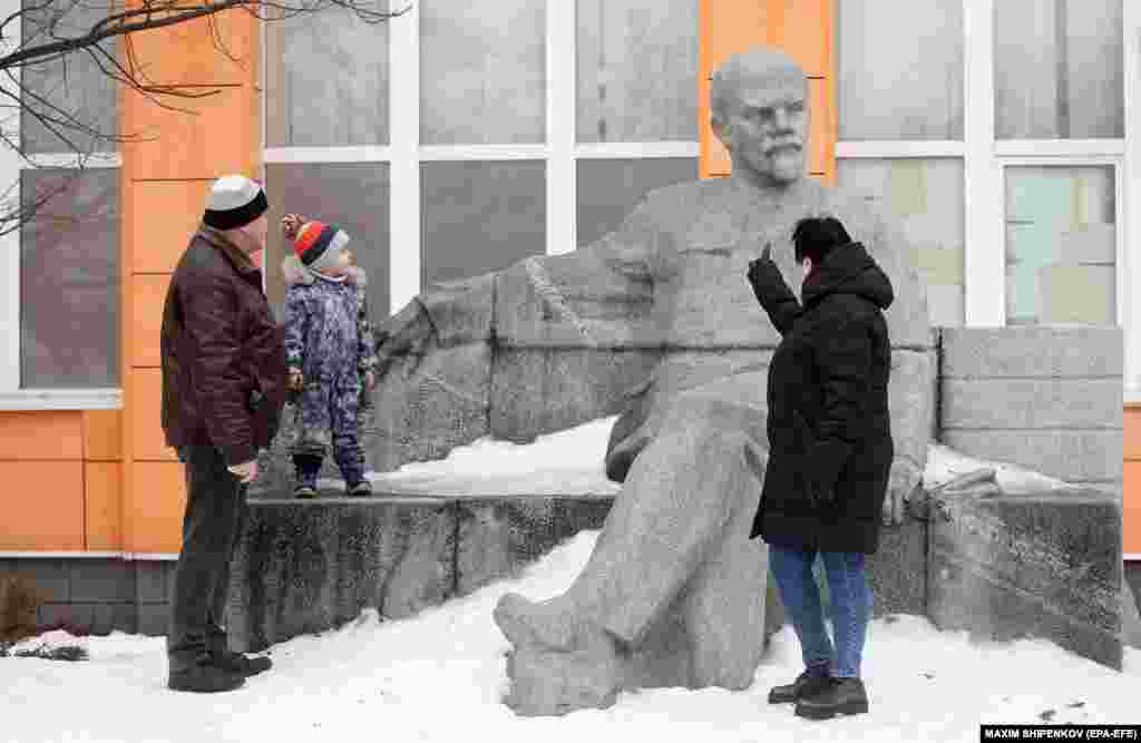 People talk in front of a monument to the founder of the Soviet Union, Vladimir Lenin, at Lenin State Farm outside Moscow.&nbsp;