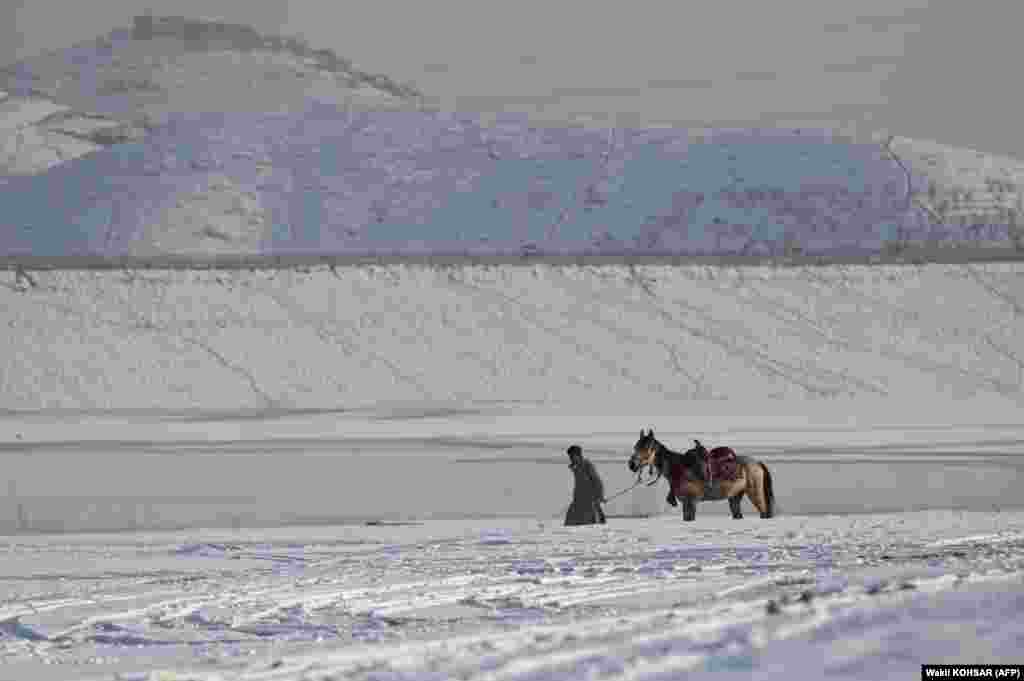An Afghan youth and his horse walk along Qargha Lake on the outskirts of Kabul on January 26.
