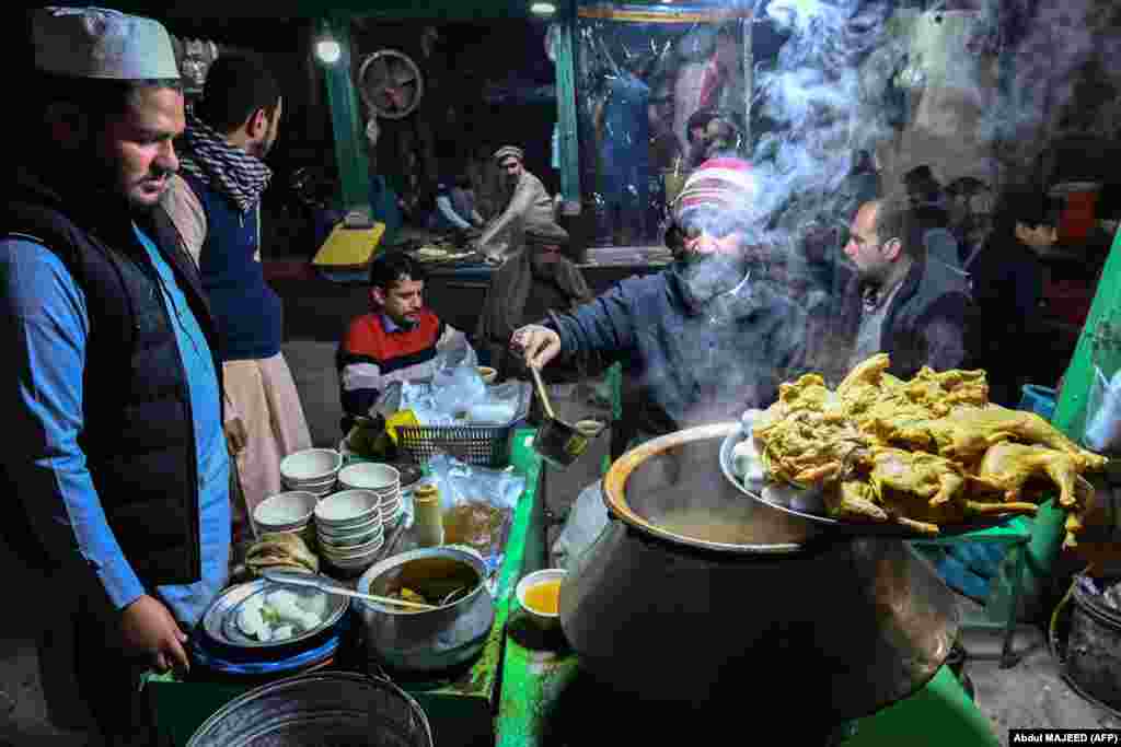 A vendor serves warm soup for customers at a street stall during a cold winter evening in Peshawar, Pakistan.