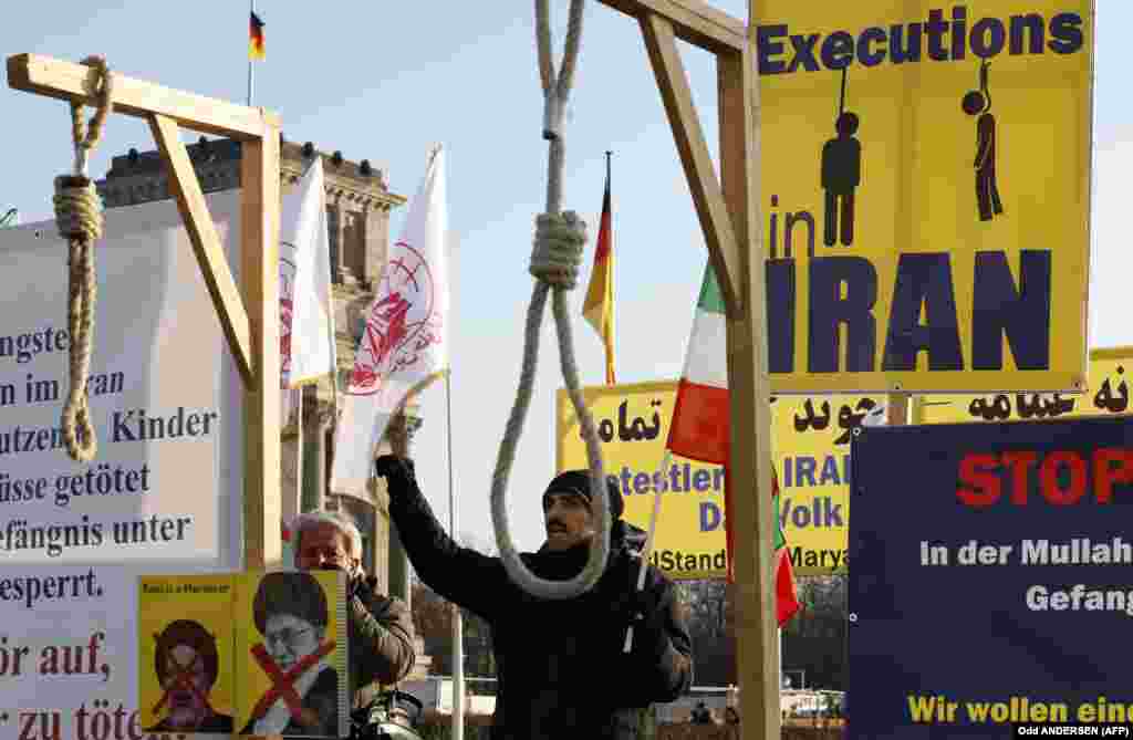 Activists of the Exile-Iranian Society hold placards and gallows as they demonstrate in solidarity with anti-government protesters in their home country in front of the Reichstag, Berlin.