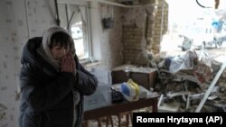 Жінка у своєму зруйнованому будинку після російського ракетного обстрілу в Глевасі на Київщині, 26 січня 2023 року