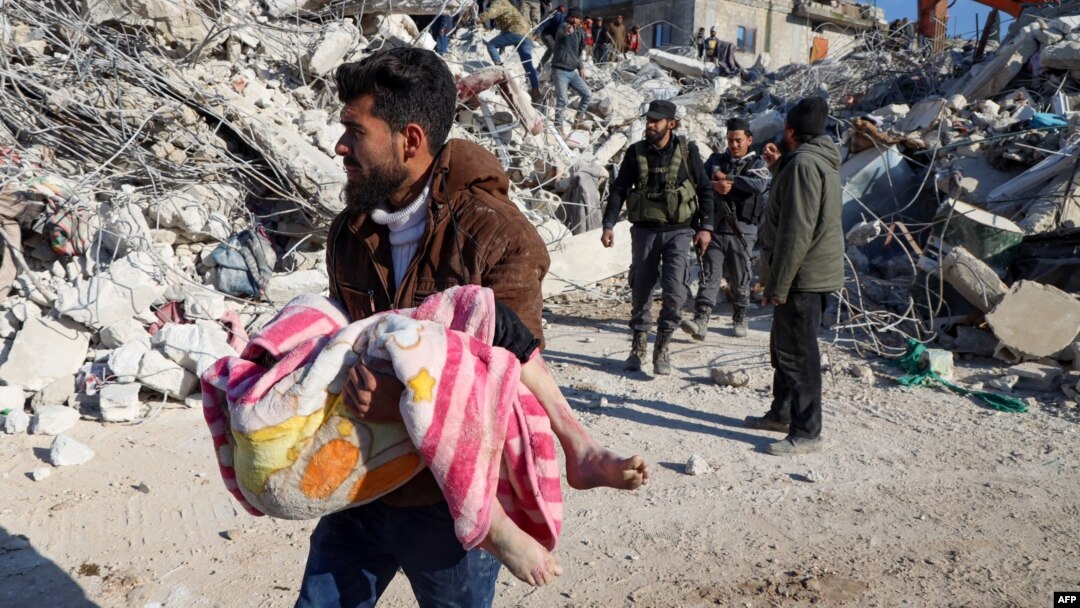 Un bărbat cară trupul unui copil scos dintre dărâmături în orașul Harim, în provincia siriană Idlib, aflată în nord-vestul țării și controlată de rebeli, 8 februarie 2023.