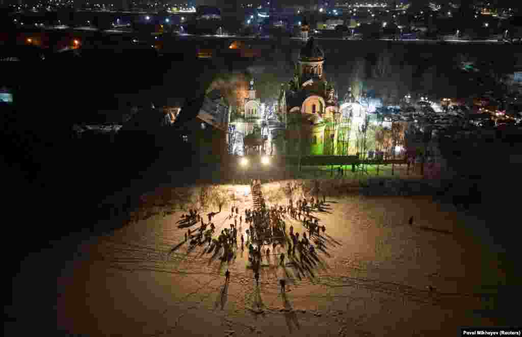 People plunge into ice-cold water as others gather around an ice hole during celebrations of the Orthodox Christian feast of Epiphany in Almaty, Kazakhstan.