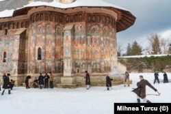 Tinerii se joacă în zăpadă în fața Mănăstirii Moldovița din județul Suceava.