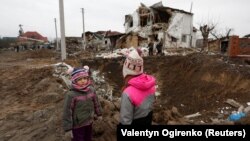 Copii lângă craterul unei rachete rusești în localitatea Hlevaha din apropiere de Kiev, 26 ianuarie 2023.