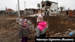 Children stand next to a crater left by a Russian military strike in the town of Hlevakha, outside Kyiv, on January 26.